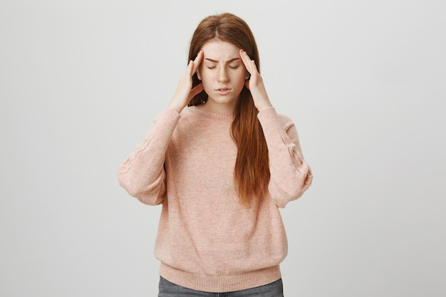 Redhead female student having headache, suffer migraine