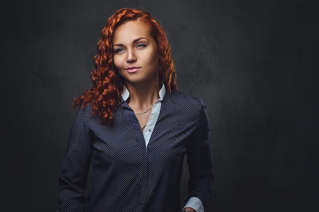 Redhead female supervisor dressed in an elegant suit over grey background.