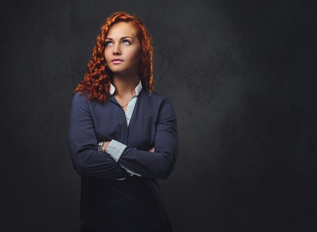 Redhead female supervisor dressed in an elegant suit over grey background.