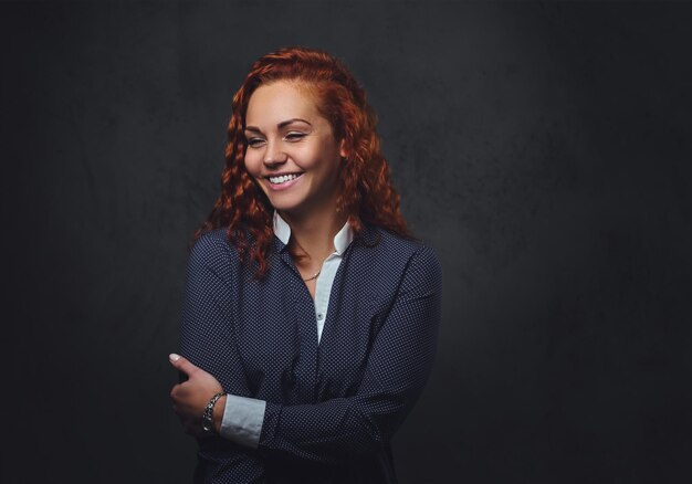 Redhead female supervisor dressed in an elegant suit over grey background.