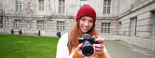 無料写真 赤毛の女の子の写真家が屋外でプロのカメラで写真を撮り、ストリート スタイルのショットをキャプチャします