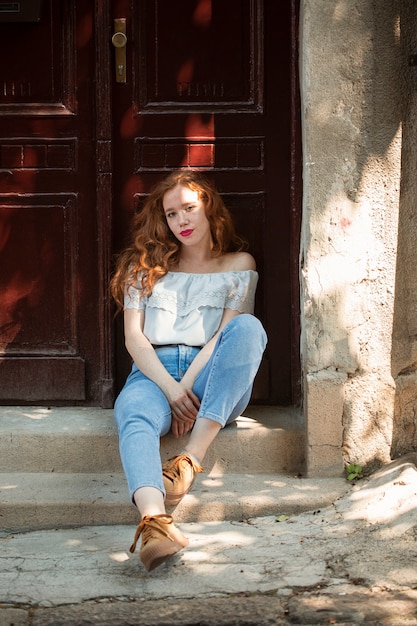 Redhead girl posing in front of a door