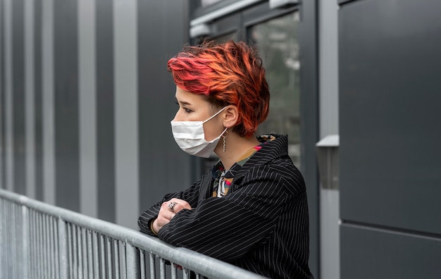 屋外で医療用マスクを着用している赤毛の非バイナリ人