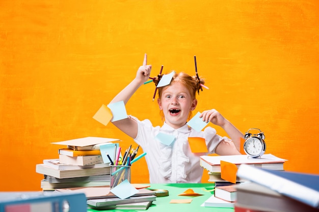 The redhead teen girl with lot of books at home. studio shot