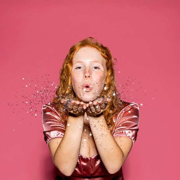 Redhead woman blowing confetti