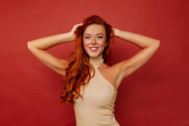 redhead woman in elegant dress posing on red