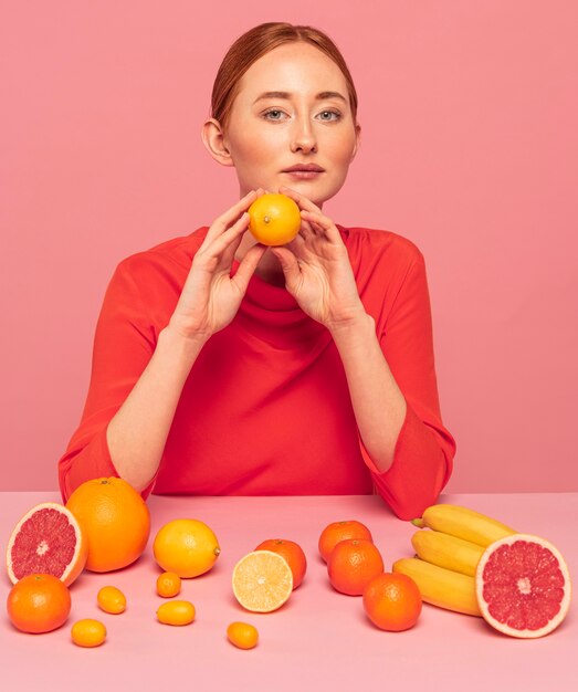 Рыжая женщина, держащая апельсин