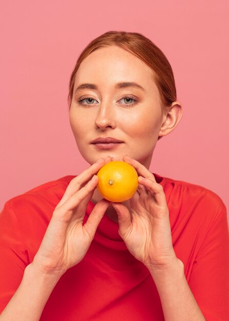 オレンジを保持している赤毛の女性