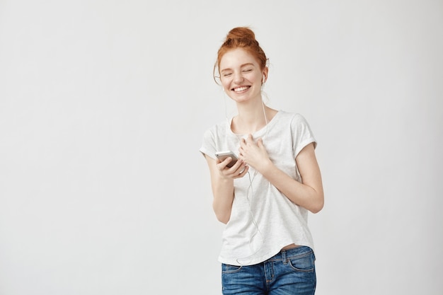 redhead woman listening music in headphones laughing.