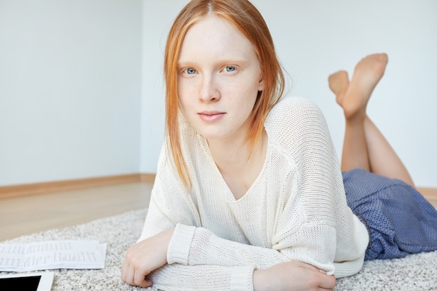 Redhead woman lying on floor with notebook and tablet