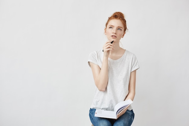 Free photo redhead woman making notes thinking sitting