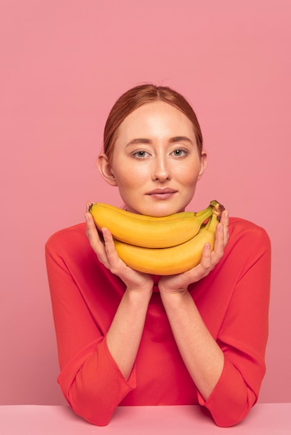 Рыжая женщина позирует рядом с бананами