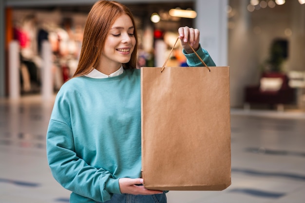 Redhead woman showing a paper bag