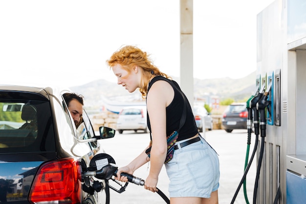 赤毛の女性がガソリンスタンドで車に給油