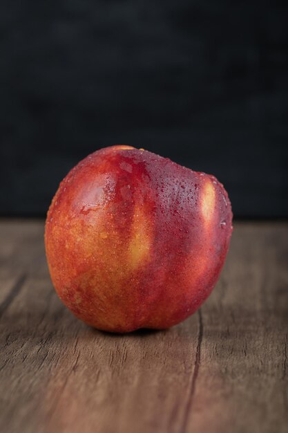 Free photo redish peaches isolated on wooden table.