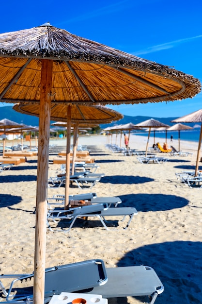 Reed umbrellas and sun beds at the empty beach