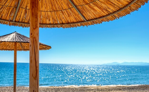 Reed umbrellas and sun beds at the empty beach