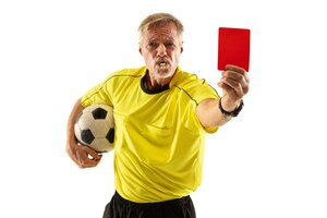 Рефери держит мяч и показывает красную карточку футболисту или футболисту во время игры на белом фоне студии.