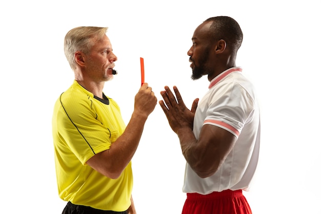 Arbitro che mostra un cartellino rosso a un giocatore di football o di calcio afroamericano dispiaciuto durante il gioco isolato su sfondo bianco.