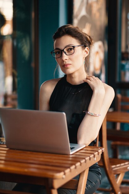 Refined business woman in glasses, sitting at table in cafe work