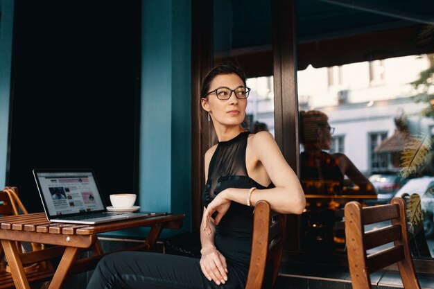 Refined business woman in glasses, sitting at table in cafe work