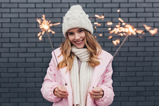 Refined caucasian girl spending winter holidays in good mood. Outdoor portrait of dreamy young woman with sparklers having fun.