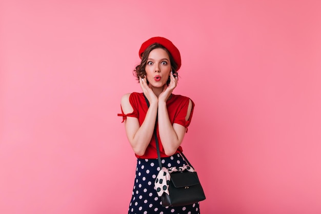 Refined caucasian woman in vintage french attire posing in studio Indoor shot of amazed brunette lady isolated on pastel background