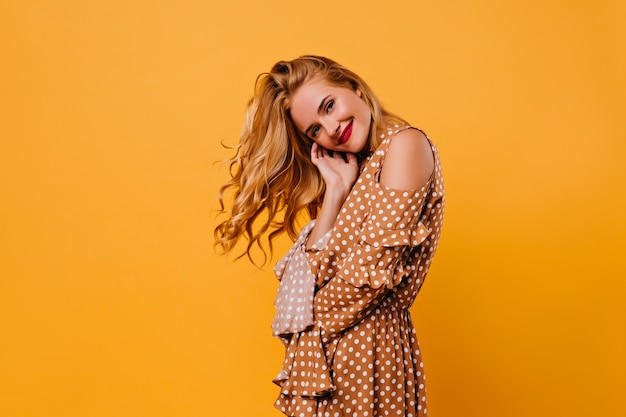 Refined white female model with gentle smile. Indoor shot of blissful woman in brown dress.