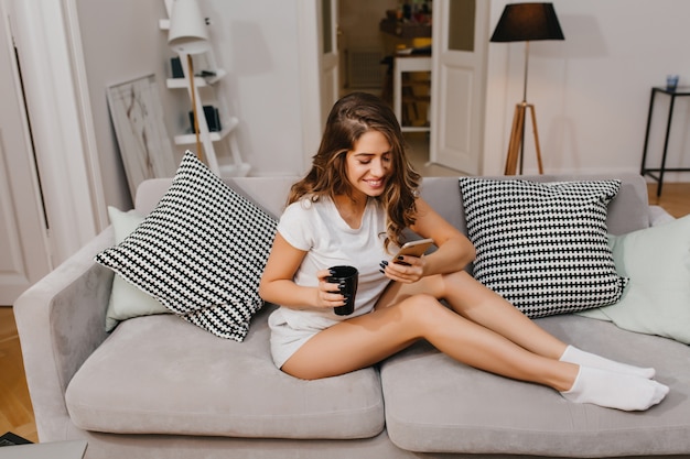 朝にコーヒーを飲み、電話メッセージを読んで洗練された女性