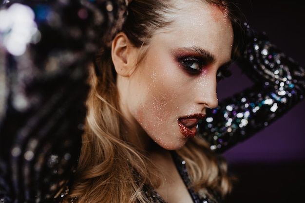 Refined woman in sparkle attire posing on dark background Closeup portrait of sensual white lady