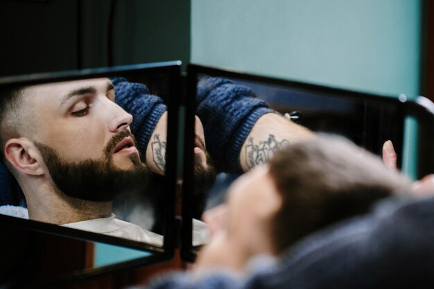 Reflection of bearded man in barbershop mirror