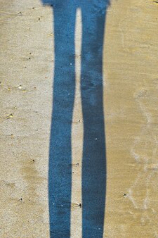 濡れた​砂​の​上​の​足​の​海​の​日当たり​の​良い​影​による​砂​の​上​の​足​の​反射