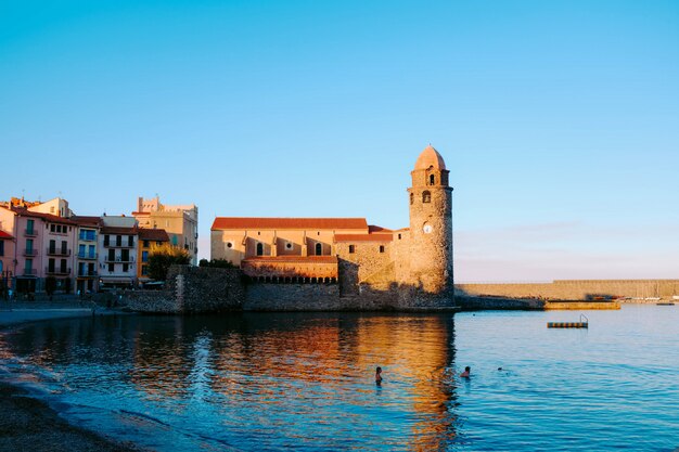 Reflection of an old castle in the calm water of the sea under the blue sky