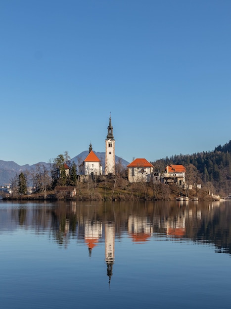 The reflection of an old castle on the water surrounded by trees and mountains