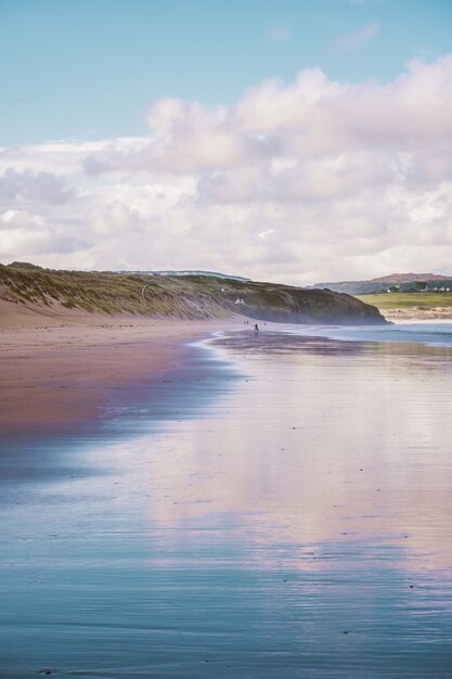 Отражение неба в море на пляже в Корнуолле, Англия