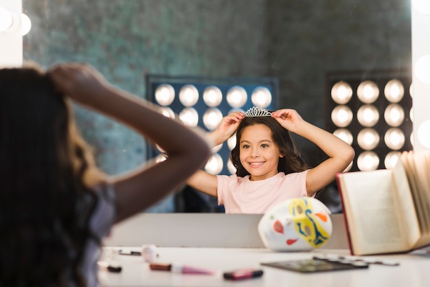 Free photo reflection of smiling girl wearing crown at backstage