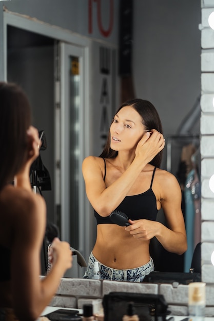 Reflection of young beautiful woman applying her make-up