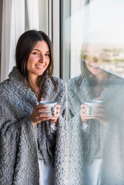 Reflective smiling portrait of woman holding coffee cup in hand