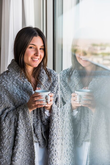 Reflective smiling portrait of woman holding coffee cup in hand