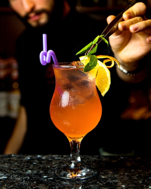 Освежающий коктейль с кусочками льда, ломтиками лимона и листьями мяты