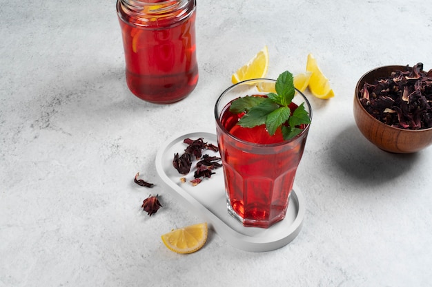 Foto gratuita tè freddo rinfrescante all'ibisco in contenitore di vetro trasparente