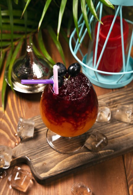 Refreshing red grape beverage in glass with ice cubes