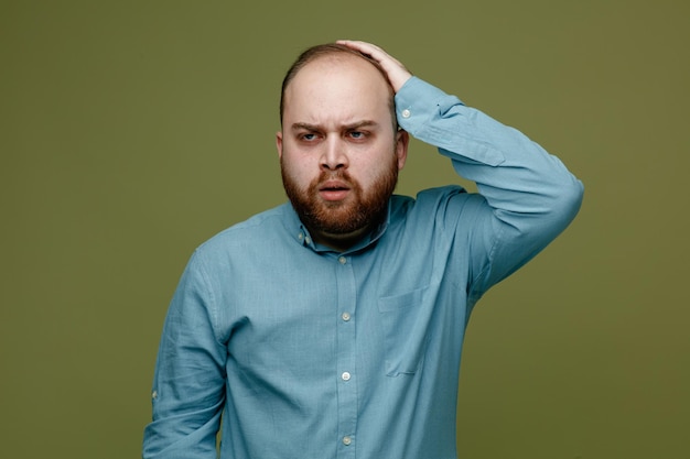 Foto gratuita il rimpianto ha afferrato la testa del giovane bel ragazzo che indossa una camicia blu isolata su sfondo verde