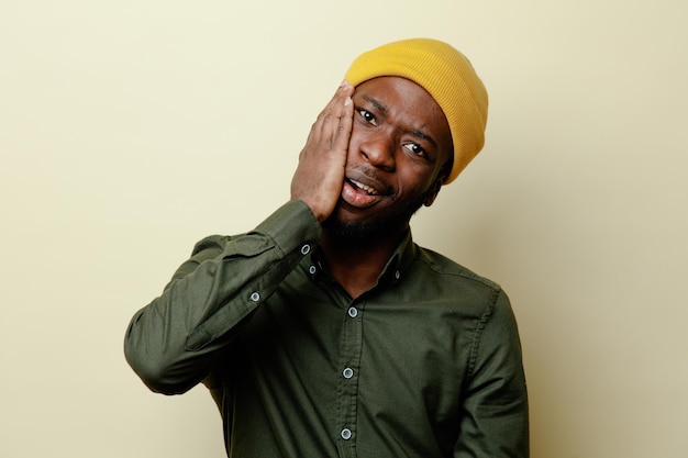 Free photo regret putting hand on face young african american male in hat wearing green shirt isoloated on white background