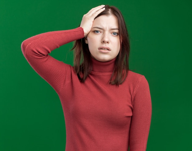 Regretting young pretty girl keeping hand on head 