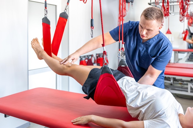 Rehabilitation specialist doing treatment on suspension straps to patient