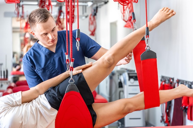 Free photo rehabilitation specialist doing treatment on suspension straps to patient