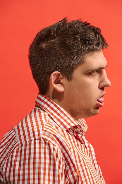 Free photo reject, rejection, doubt concept. doubtful man with thoughtful expression making choice. young emotional man. human emotions, facial expression concept. front. studio. isolated on trendy red. profile