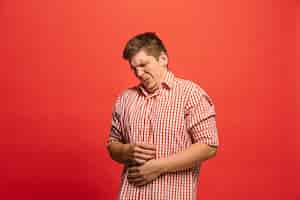 Free photo reject, rejection, doubt concept. doubtful man with thoughtful expression making choice. young emotional man. human emotions, facial expression concept. front. studio. isolated on trendy red