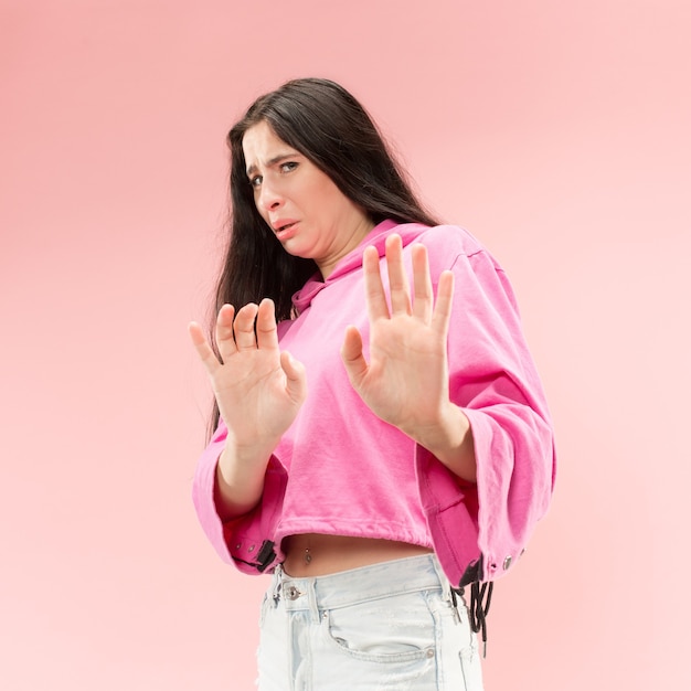 Reject, rejection, doubt concept. Doubtful woman with thoughtful expression making choice. Young emotional woman. Human emotions, facial expression concept. Studio. Isolated on trendy pink